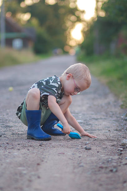 istock Boy playing with toy shovel on a rural road 2236476395