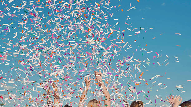 istock High school graduates joyfully throwing vibrant confetti in celebration against a clear blue sky 2236476936