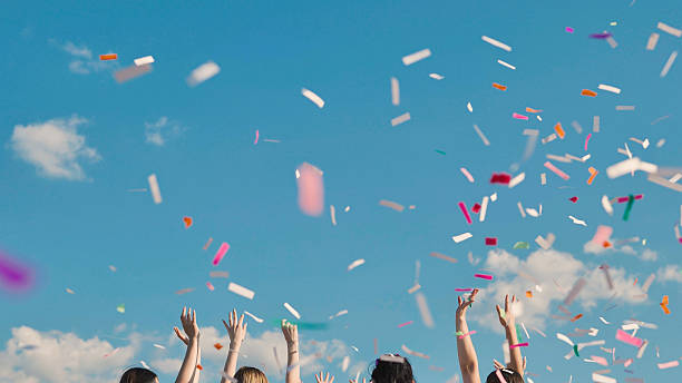 istock High school graduates joyfully tossing confetti under a sunny blue sky 2236477356