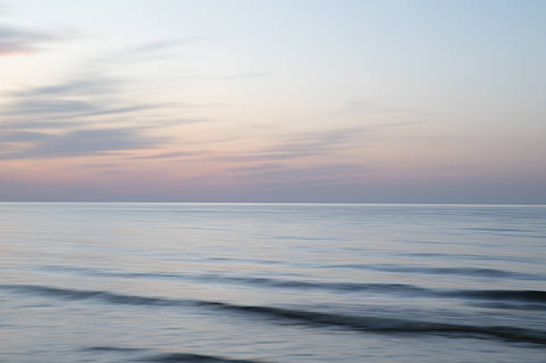 A dreamy, impressionistic paint like blurred sea sunset background with gently soft pastel colours. Vertical photo.