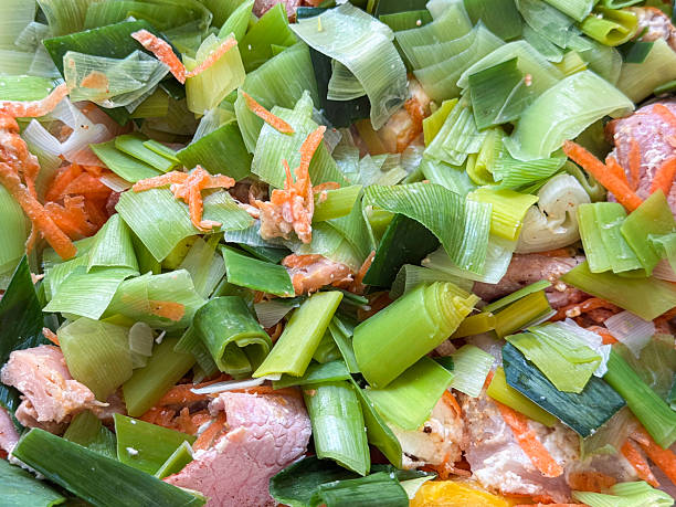 Stock photo shows a homemade fish pie with cod and smoked haddock, combined with grated carrots, sliced leeks, and bacon. This image showcases fresh ingredients and step-by-step recipe preparation, highlighting wholesome, flavorful cooking