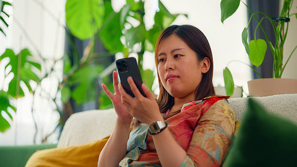 istock Woman sits at sofa and uses her smartphone at home 2236483297