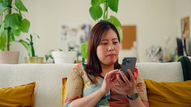 istock Woman sits at sofa and uses her smartphone at home 2236483320
