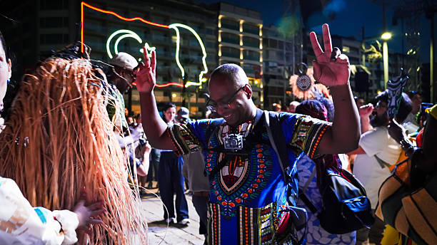 Back view of large group of embraced friends having fun on music festival by night.