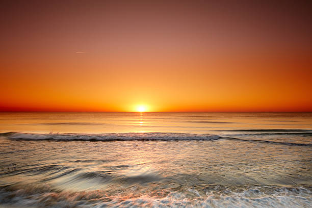 Vivid sunset over a serene ocean horizon reflecting warm hues