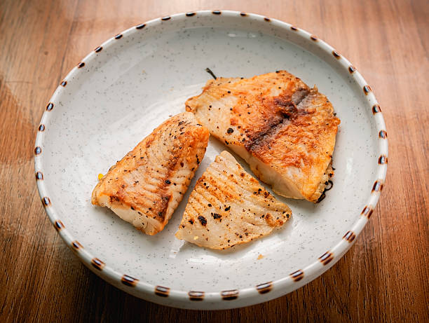 istock Grilled fish pieces placed on a white ceramic plate on a wooden background. 2236503658
