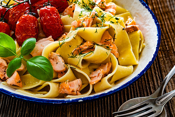 istock Pasta with baked salmon and cherry tomato on wooden table 2236509619