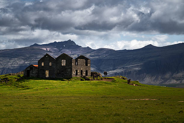 A farm sits quietly at the foot of mountains in Iceland