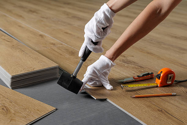 Woman aligning SPC vinyl plank with mallet on underlayment during installation