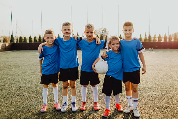 istock Junior soccer team posing together on the field in blue uniforms 2236520111
