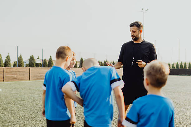 istock Coach instructing junior football team 2236520129