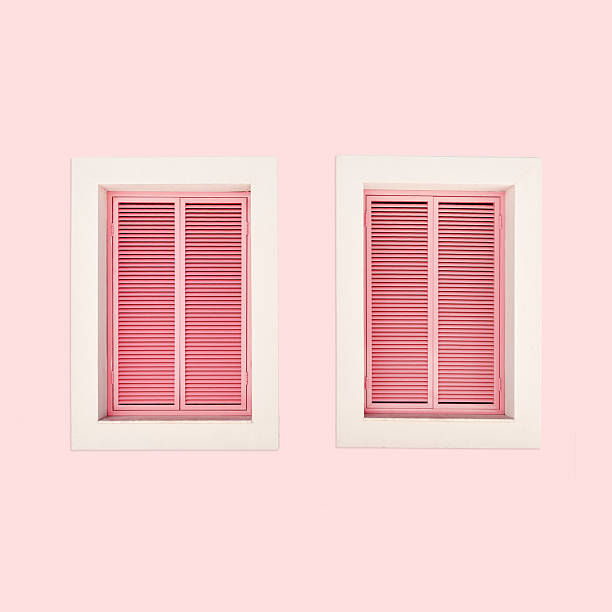 Minimal summer aesthetic two pink shutter windows on pastel pink wall. Natural sunlight creates soft shadows, modern design. Concepts of summer, vacation, tropical style, architecture, home decor