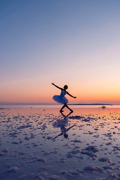istock Ballerina dancing gracefully on a salt flat at sunset with reflection 2236532858