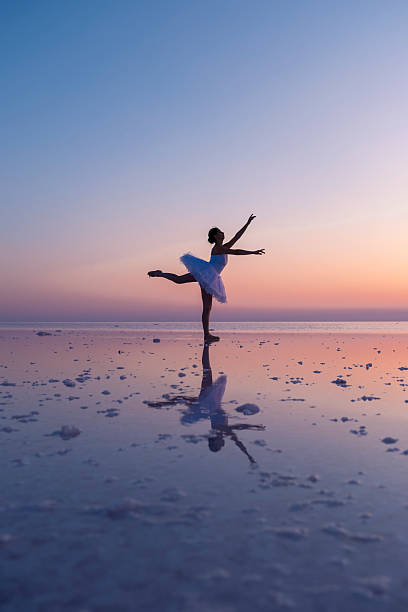 istock Ballerina dancing en pointe on a salt flat with sunset reflection 2236532862
