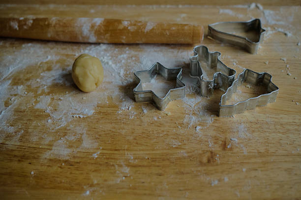 Photo of the baking process. Dough and cookie cutters on a wooden table. The concept of home cooking, baking, festive sweets and culinary creativity.
