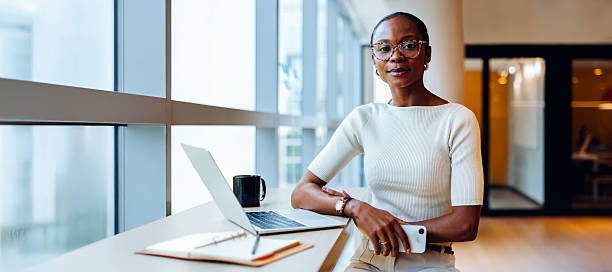 istock Confident professional woman seated by a window with laptop and notes 2236542976