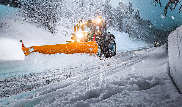 Snowplow Tractor Clearing Road During Heavy Snowfall