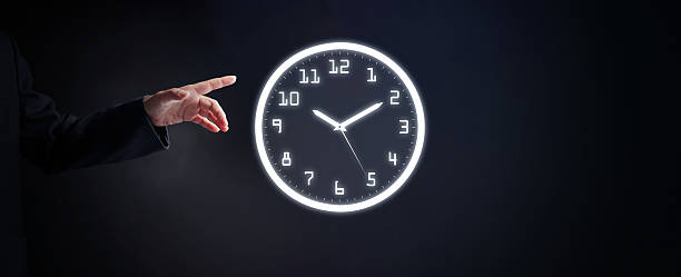 istock Businessman pointing at a glowing wall clock on dark background, symbolizing time management, resource control, business planning, efficiency, and strategic productivity improvement. 2236546939