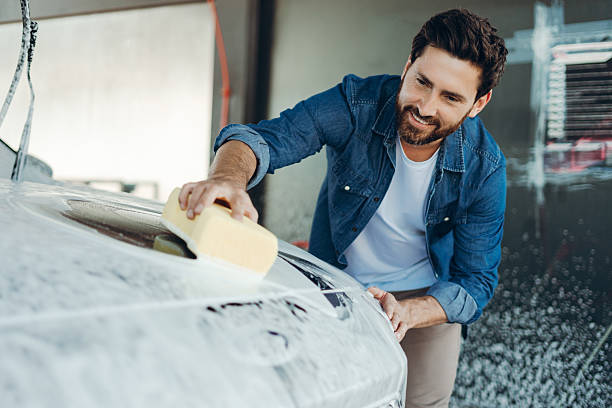 istock Man washing car with sponge, smiling happily 2236553215