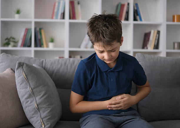 The boy who feels a stomachache is holding his stomach