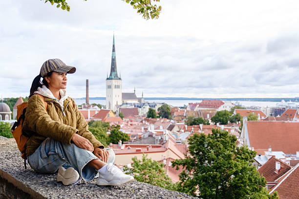 An Asian woman sits peacefully on a stone ledge, taking in the stunning views of Tallinn Old Town Estonia.