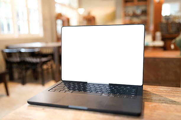 istock Modern laptop computer with blank screen sits on wooden table in a trendy cafe setting, showcasing a blurred background of warm lighting 2236570280