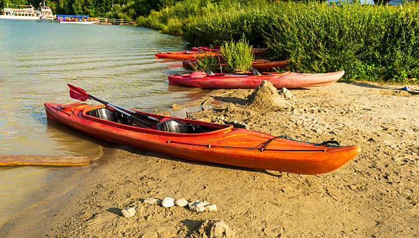 istock Bright red kayak on sandy riverbank 2236570351