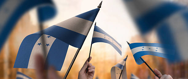 istock Honduras flags in their hands on a blurred urban background 2236572266