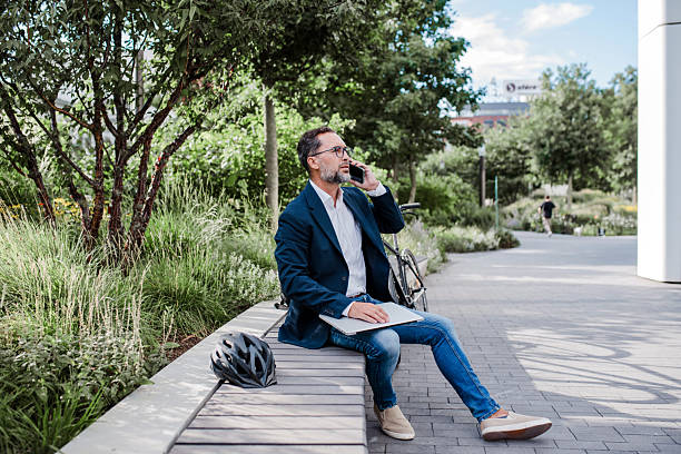 istock Business commuter taking a break with bicycle in urban park, making phone call. 2236572831