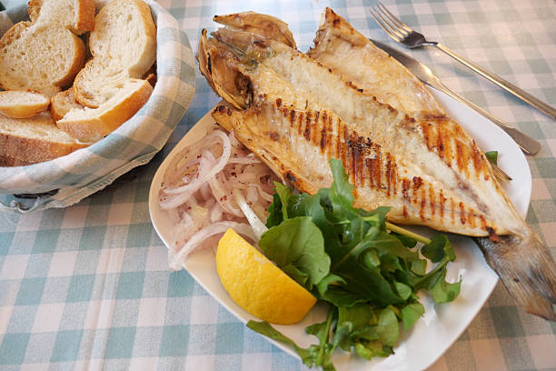 istock Grilled fish served with salad and bread on checkered tablecloth 2236575575