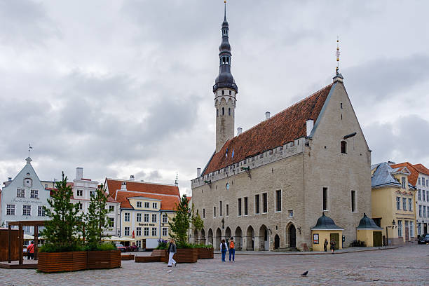 Tallinn, Estonia, 26 August 2025, Visitors stroll through the charming Town Hall Square, surrounded by stunning medieval architecture under moody, overcast skies.