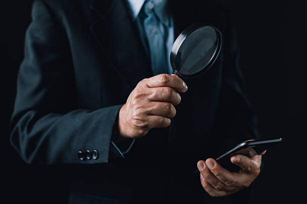 istock businessman holds smartphone and inspects it closely using a magnifying glass, symbolizing investigation, digital scrutiny, cybersecurity analysis, search engine or detailed mobile data examination. 2236577929