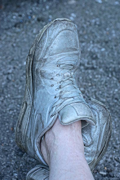 istock two gray old dirty leather sneakers on a man feet 2236578883