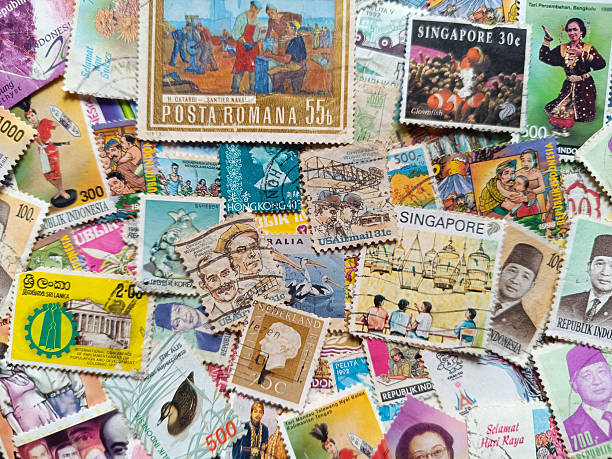 Many vintage stamps are scattered on a flat surface showing different designs and colors. The stamps feature historical figures and are from various countries.