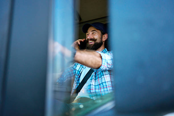 istock Truck driver talking on phone while smiling and driving 2236588673
