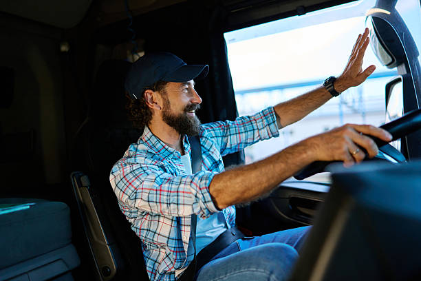 istock Happy truck driver smiling and waving while driving 2236588681