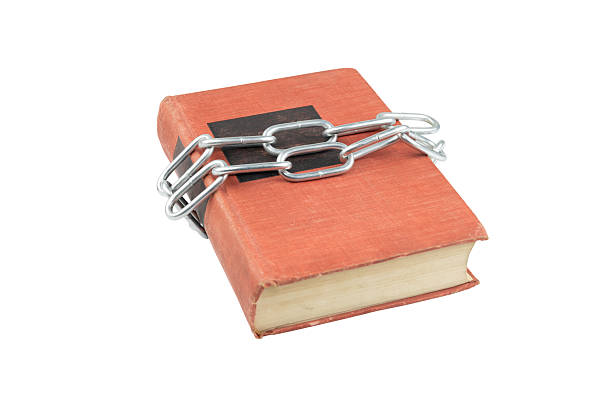 istock Orange hardcover book bound with metal chain isolated on white background with clipping path. 2236592113