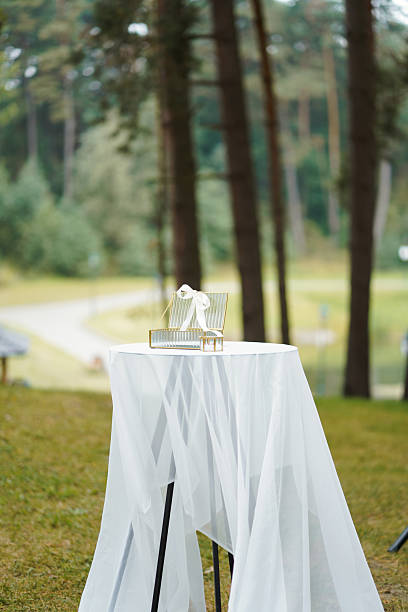 istock Glass box with a ribbon placed on a table covered with white fabric outdoors. 2236598503