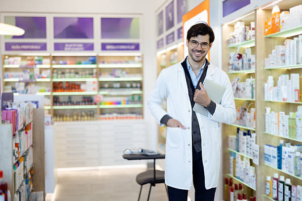istock Smiling male pharmacist standing in modern pharmacy store 2236601550
