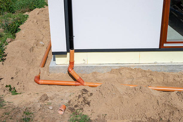 istock Underground drainage pipe installation next to residential building foundation during construction. 2236602215