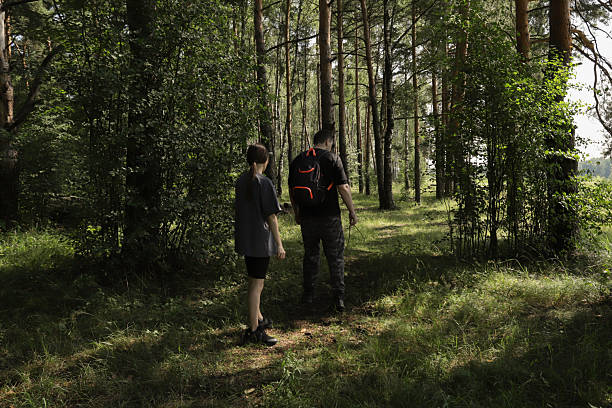 istock Two people picking mushrooms in the forest, moving carefully through grass and shadows, concept of outdoor learning, seasonal foraging, and mindful nature time. 2236610445