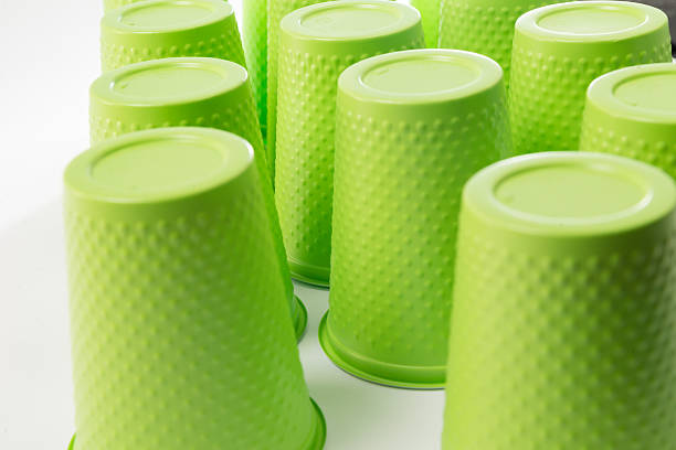 a lot of green plastic drinks cups, disposable plastic tableware, dangerous to the environment, new cups closeup