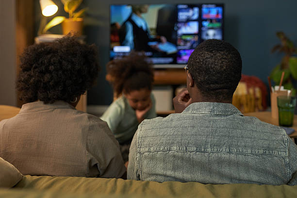 istock Black Parents Watching Television While Young Child Playing in Living Room 2236614480