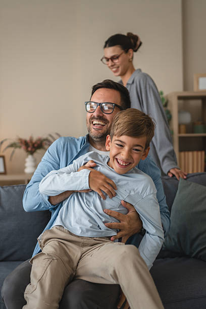 istock Family enjoying a fun tickling moment on sofa 2236614673