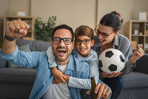 istock Happy family cheering for favorite team at home 2236614876