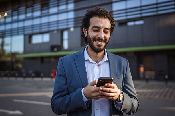 istock Smiling businessman using smart phone in front of office building 2236616160
