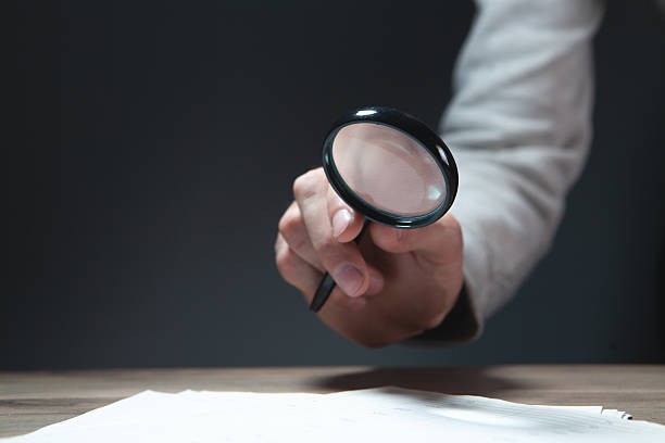 istock Hand holding a magnifying glass and writing on paper, selective focus 2236616411