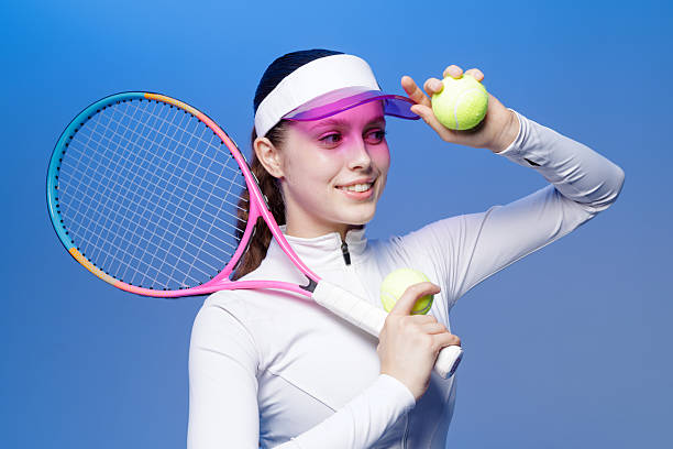 istock Smiling female tennis player with racket and balls on blue studio background 2236620453