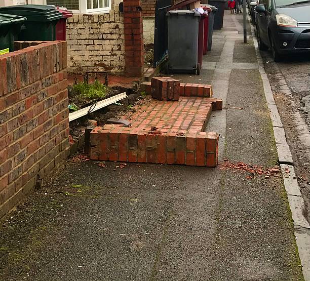 istock Broken Red Brick Wall and Pavement Damage in Urban Area 2236620624
