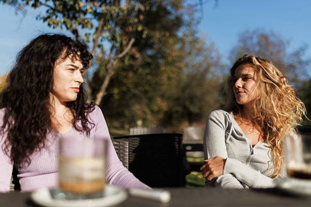 istock Friends enjoying conversation outdoors on a sunny day at a cafe patio with drinks and a relaxed atmosphere surrounded by nature 2236625336